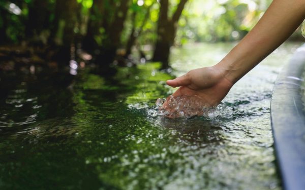 Person sailing on boat and touching water with hand